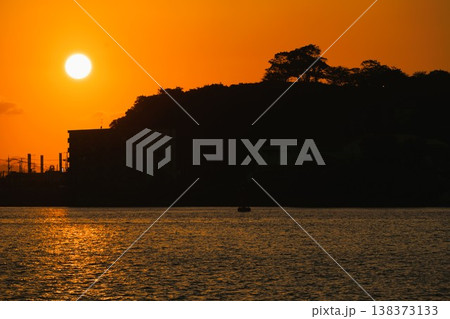 海辺の街を照らす夕日と水面の輝き 138373133