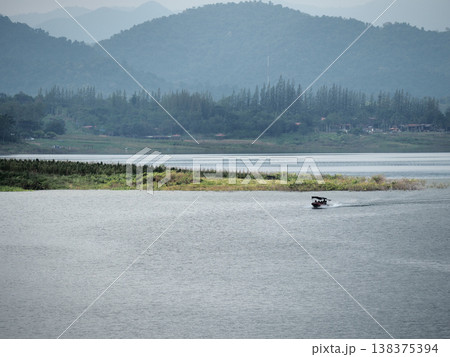 Serene lake small boat mountain landscape cloudy sky forest shoreline tranquil water Serene lake with small boat crosses Serene lake small boat mountain landscape cloudy sky forest shoreline tranquil water Serene lake with small boat crosses 138375394