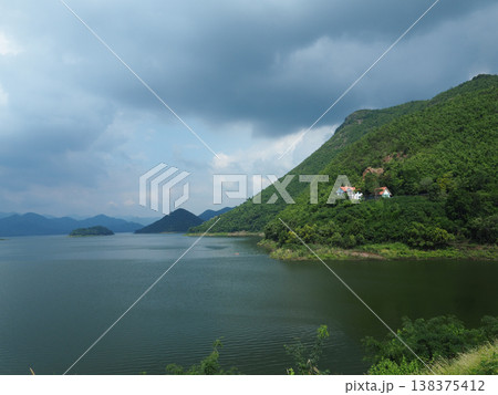 Lake mountain green hill cloudy sky calm water distant island rural house scenic landscape tranquil view with lush nature Lake mountain green hill cloudy sky calm water distant island rural house scenic landscape tranquil view with lush nature 138375412
