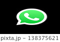 The iconic WhatsApp logo featuring a green speech bubble with a white telephone symbol, set against a stark black background. Represents global communication and instant messaging. 138375621