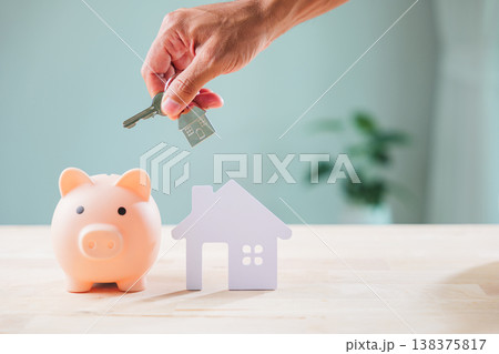 Ensuring cyber bank piggy security for saving, Privacy measures are crucial, hand presents house key over house model, illustrating diligent financial planning for future property investment, 138375817