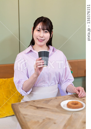 カフェでコーヒーとドーナツを楽しむ笑顔の女性 カフェでコーヒーとドーナツを楽しむ笑顔の女性 138376151