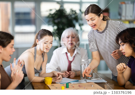 Emotional female colleagues of business company different ages playing exciting board game in office 138376196