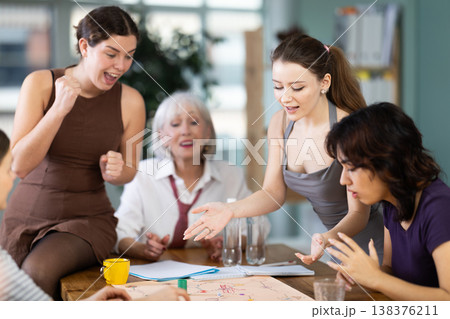 Group of women playing board game around a table Group of women playing board game around a table 138376211