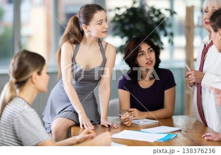 Young girl standing and leading a group discussion with diverse ladies 138376236