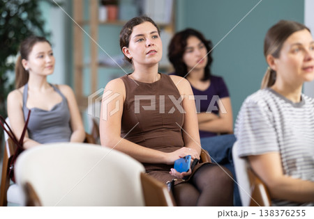 Young woman sitting on chair and listening to presentation 138376255