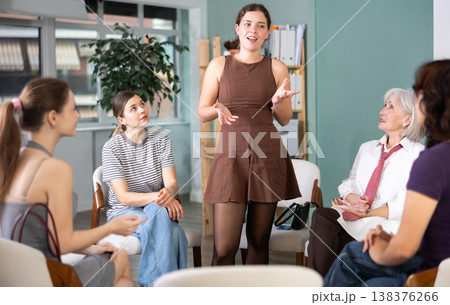 Young female speaker address to member of community, woman standing next to seated audience 138376266
