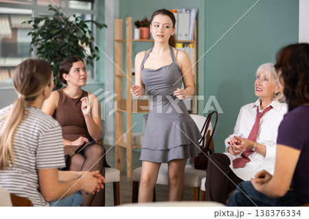 Young female speaker address to member of community, woman standing next to seated audience 138376334