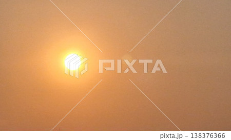 Abstract cinematic background of a bright sun glowing through heavy haze with soft warm orange tones. 138376366