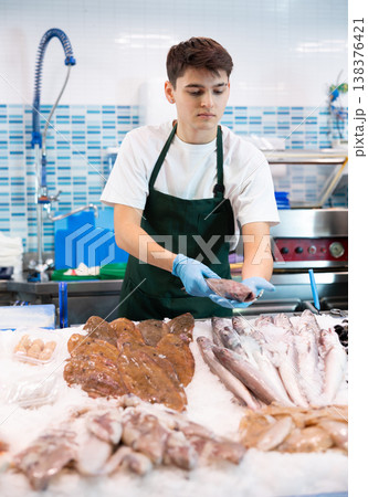 Positive salesman demonstrating lucet fish in fish store Positive salesman demonstrating lucet fish in fish store 138376421