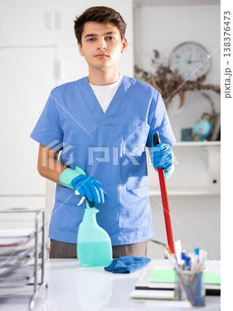 Portrait of positive male cleaner in protective uniform at company office 138376473