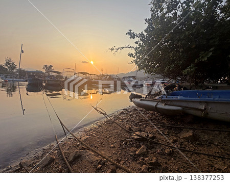 Boats moored at a tranquil harbor during a serene golden hour sunset 138377253