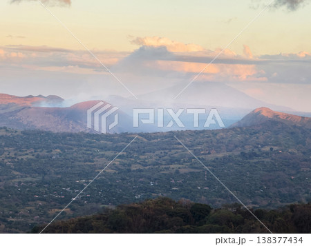 View of smoke rising from hills in the sunset over a valley 138377434