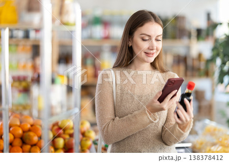 Young woman scanning qr code of soy sauce Young woman scanning qr code of soy sauce 138378412