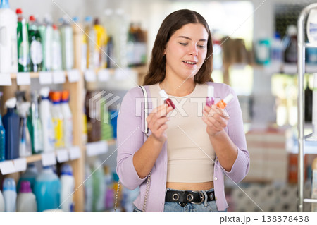 Female buyer chooses nail polish in household goods department of supermarket Female buyer chooses nail polish in household goods department of supermarket 138378438