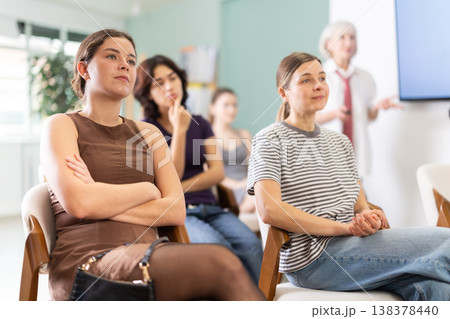 Female students are sitting in study room. Coach speaker telling in background. 138378440