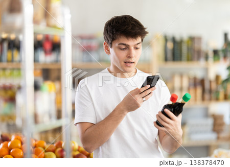 Male buyer checks suitability - scans QR code on jar of soy sauce label in grocery store 138378470
