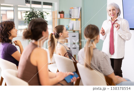 Senior woman coach speaks to audience of listeners, carry out lecture. Senior woman coach speaks to audience of listeners, carry out lecture. 138378554