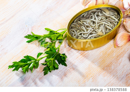 Pickled eels in open tin can with garlic at table, nobody Pickled eels in open tin can with garlic at table, nobody 138378588