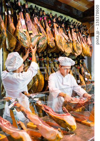 Butcher shop owner and assistant sell Spanish ham 138378600