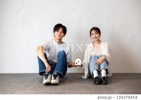 家のクラフトを持って壁際に座っている若い男女のカップル 家のクラフトを持って壁際に座っている若い男女のカップル 138378858