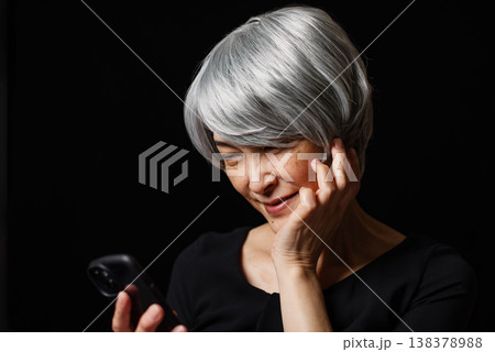 スマートフォンの画面を眺めながら微笑むシニア女性 スマートフォンの画面を眺めながら微笑むシニア女性 138378988