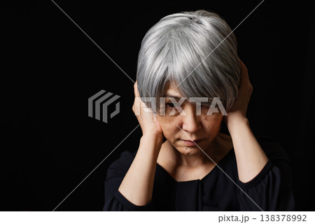 両手で耳をふさぐ暗い表情のシニア女性 138378992