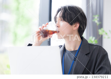 仕事の合間にコーヒーや飲み物で休憩する若手社員のリフレッシュシーン 仕事の合間にコーヒーや飲み物で休憩する若手社員のリフレッシュシーン 138379211
