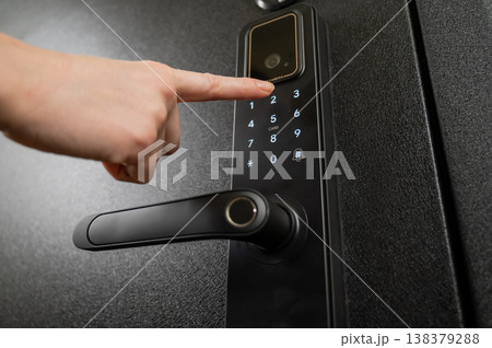 A woman opens a modern smart door lock with a digital keypad using a code. 138379288