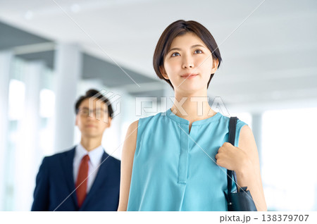 明るい表情で未来を見据えるオフィス街のビジネスウーマンと背後の同僚 138379707