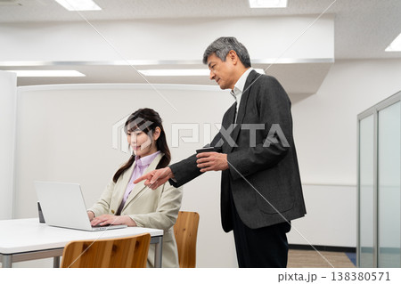 オフィスで部下の女性にアドバイスをする上司の男性 138380571