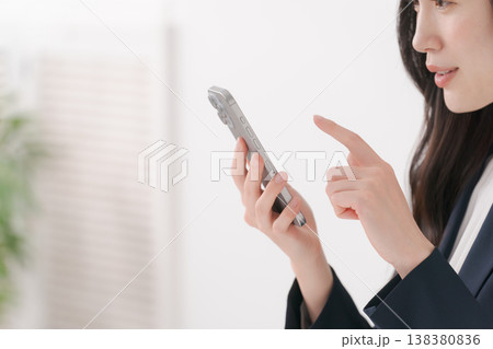 スマホを操作するスーツの女性 138380836