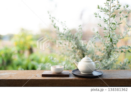 White tea cup and tea pot on wooden table, relax drinking at balcony White tea cup and tea pot on wooden table, relax drinking at balcony 138381362