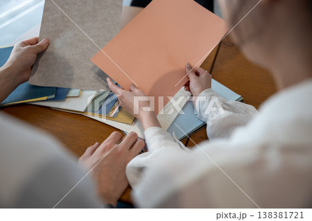 壁紙サンプルを持って相談する若いカップルの手元 壁紙サンプルを持って相談する若いカップルの手元 138381721