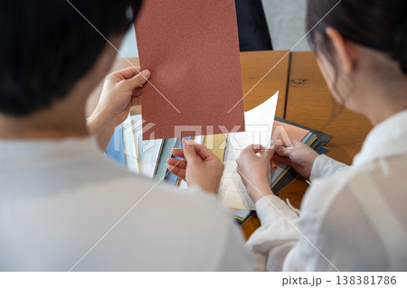 壁紙サンプルを持って相談する若いカップルの後ろ姿 138381786