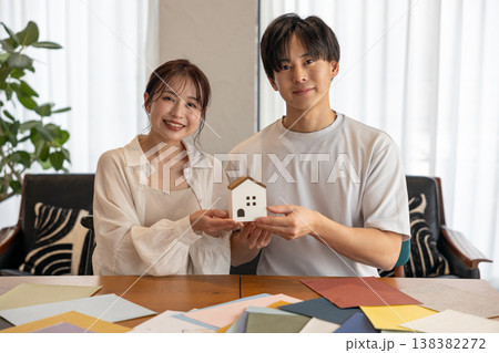 家のオブジェを持って微笑む若いカップル 家のオブジェを持って微笑む若いカップル 138382272