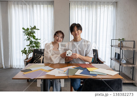 家のオブジェを持って微笑む若いカップル 家のオブジェを持って微笑む若いカップル 138382273