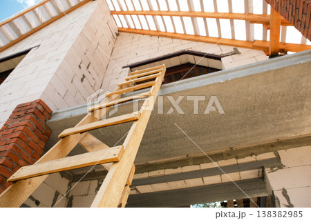 Modern house, partial scaffolding, completed attic frame and wooden roof lags, Euro-style external finish, construction technology. 138382985