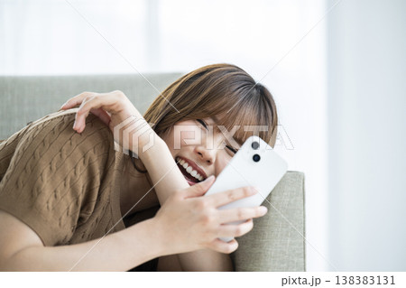 若い女性 スマホ 笑顔 カメラ目線 ソファー 若い女性 スマホ 笑顔 カメラ目線 ソファー 138383131