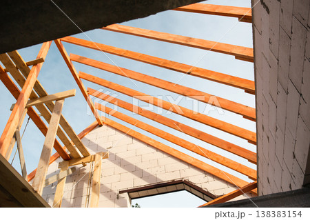 Interior roof view showing new timber rafters and lags being installed, modern home construction, supported by insurance and mortgage loan. Interior roof view showing new timber rafters and lags being installed, modern home construction, supported by insurance and mortgage loan. 138383154
