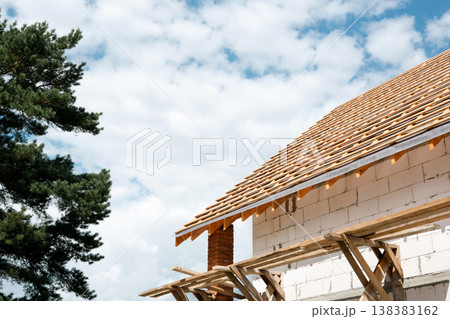 Modern white block home with visible timber lags, stropil system completes shape, light facade, European roofing technology on site. Modern white block home with visible timber lags, stropil system completes shape, light facade, European roofing technology on site. 138383162