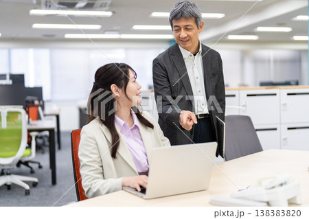 仕事の相談やアドバイスをするオフィスのビジネスマンと女性 仕事の相談やアドバイスをするオフィスのビジネスマンと女性 138383820
