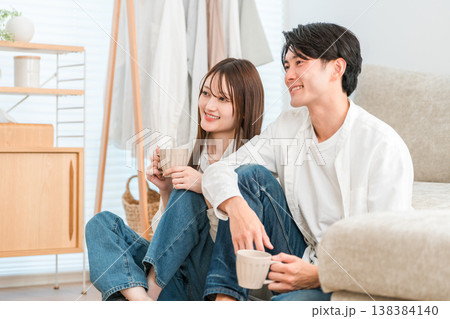 家のリビングでテレビを見る若いアジア人夫婦,カップル 138384140