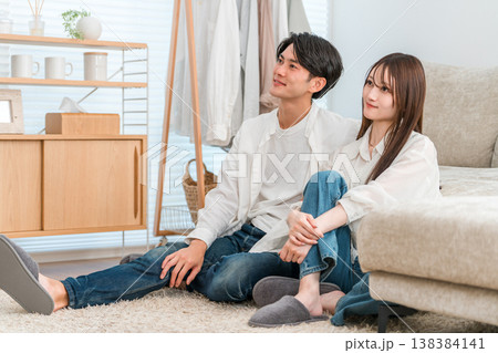 家のリビングでテレビを見る若いアジア人夫婦,カップル 138384141
