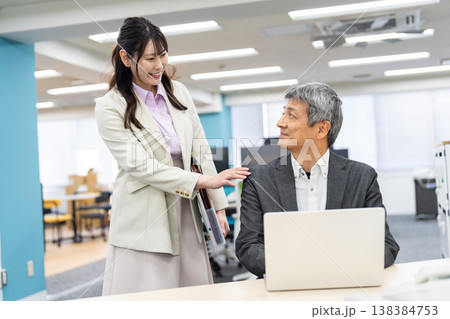 オフィスで笑顔で会話をするビジネスパーソン オフィスで笑顔で会話をするビジネスパーソン 138384753