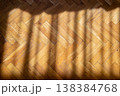 Warm wooden parquet floor with diagonal sunlight casting shadows in a herringbone pattern 138384768