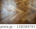 Close-up view of a warm toned oak parquet floor laid in a classic herringbone pattern 138384783