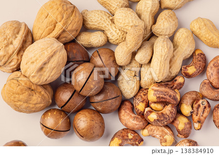 Close up of roasted mixed nuts with nutshell, walnuts, cashews, macadamia, peanuts on light brown background 138384910