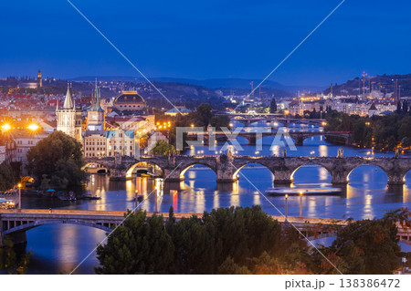 Night view of Prague with illuminated Charles Bridge over Vltava River, historic architecture and glowing city lights in famous European destination 138386472
