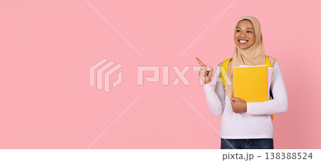 Young black Muslim woman student in hijab pointing at copy space Young black Muslim woman student in hijab pointing at copy space 138388524